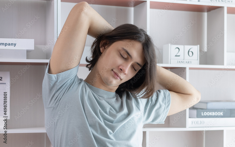 Young Asian male employee is doing a relaxing posture after a hard Midday's work, Happy men resting at work after work is finished, Fatigue is eased, Men working at home, Relax, Attractive, Success. Young Asian male employee is doing a relaxing posture after a hard Midday's work, Happy men resting at work after work is finished, Fatigue is eased, Men working at home, Relax, Attractive, Success.