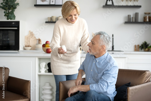Woman giving pills in bottle to her husband