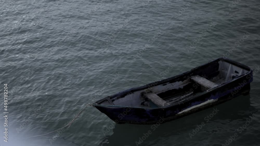 Old blue wooden boat bobs on the waves. Loneliness concept high quality 4K cinematic slowmotion footage. Old blue wooden boat bobs on the waves. Loneliness concept high quality 4K cinematic slowmotion footage.
