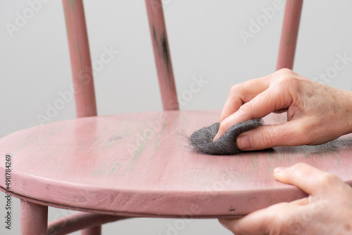 Lijando a mano de la silla de madera con lana de acero