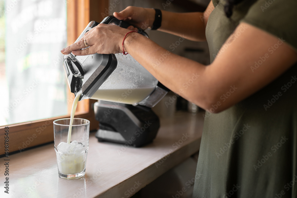 Unrecognizable woman pouring smoothie into glass Unrecognizable woman pouring smoothie into glass