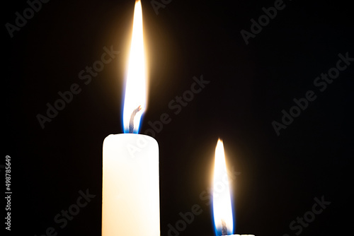 A wax candle burns in the dark.