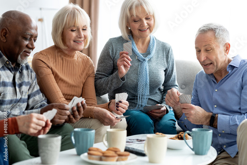Closeup of cheerful elderly people chilling together, playing cards