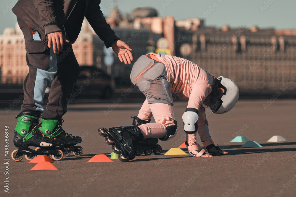Rollerball girl fell on the asphalt. The coach secures the child on roller  skates. Safe training in roller school. Stock Photo | Adobe Stock
