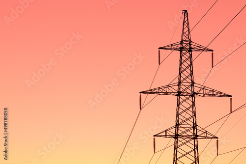 Background, view or scene of steel tower of electric main or electricity transmission line with the wires silhouette on yellow, orange and red background of sunset or sunrise sky