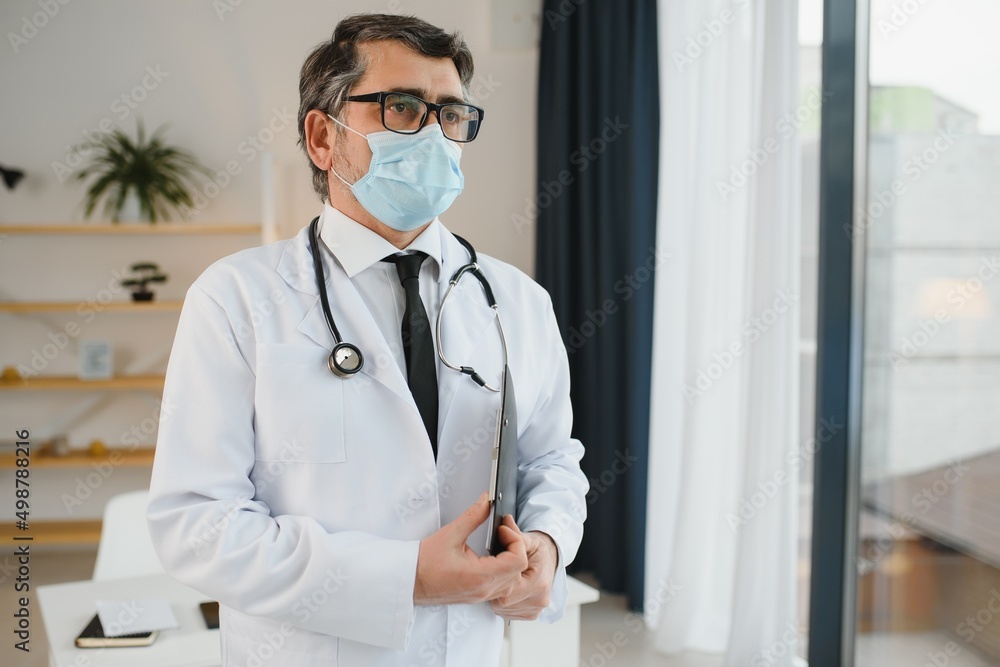 male doctor with medical face mask and a stethoscope at clinic male doctor with medical face mask and a stethoscope at clinic