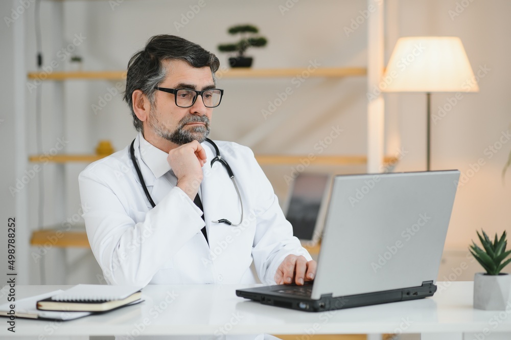 Portrait of a serious doctor using laptop in medical office Portrait of a serious doctor using laptop in medical office