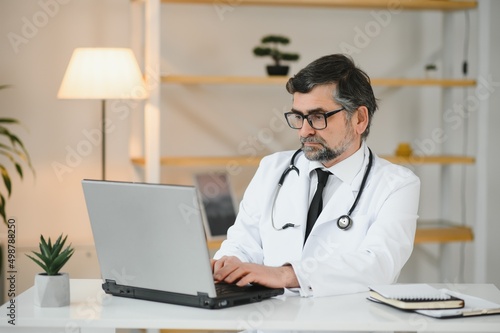 Portrait of a serious doctor using laptop in medical office