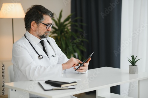 Portrait of attractive mature doctor working in office.