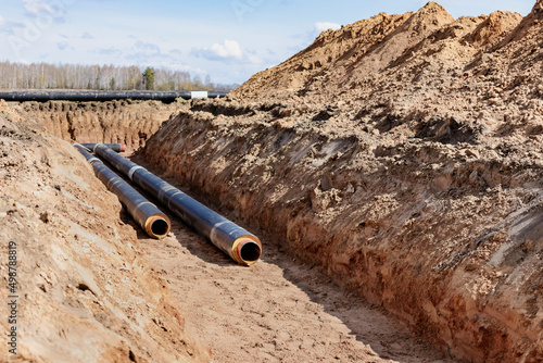 Insulated pipe. Large metal pipes with a plastic sheath laid in a trench. Modern pipeline for supplying hot water and heating to a residential area.