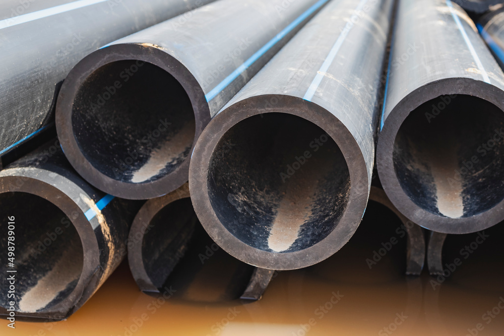 Water pipes for drinking water supply lie on the construction site. Preparation for earthworks for laying an underground pipeline. Modern water supply systems for a residential city. Water pipes for drinking water supply lie on the construction site. Preparation for earthworks for laying an underground pipeline. Modern water supply systems for a residential city.