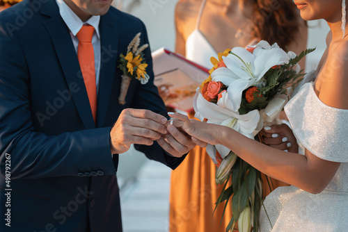 Loving couple at an international wedding at sunset. Beautiful sophisticated bride of Asian appearance. Stylish manly groom of European appearance. Mixed marriages