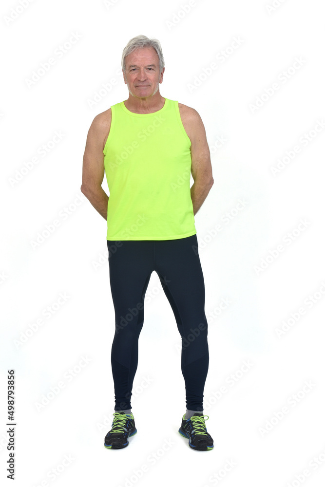 front view of a man in sportswear tights and fluorescent yellow  sleeveless looking at camera arms on back on white background