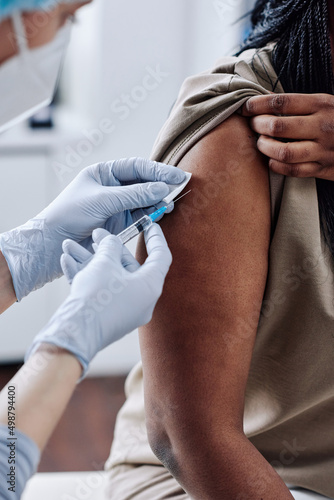 Принти на полотні Close-up of nurse in protective gloves using syringe to vaccinate African girl a
