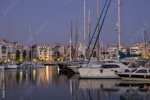 Evening coastal city, boats and yachts in the port, reflection on the water from them, in summer, Greece © Polina