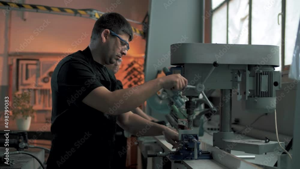 Professional workers drill a hole in a metal structure on a drilling machine in the production hall Professional workers drill a hole in a metal structure on a drilling machine in the production hall