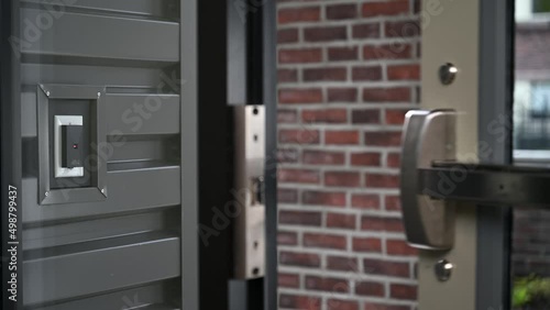 Man in a suit is standing outside of the main entrance of the  building and he touches a multi-button key fob to a keyless entry system to gain entry into the building. Shallow DOF focus on the fob photo
