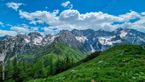 Panoramic view from the summit of Goli Vrh on rocky sharp mountains of Kamnik Savinja Alps in Carinthia, border Austria and Slovenia. Green spring meadow in Vellacher Kotschna. Mountaineering. Freedom