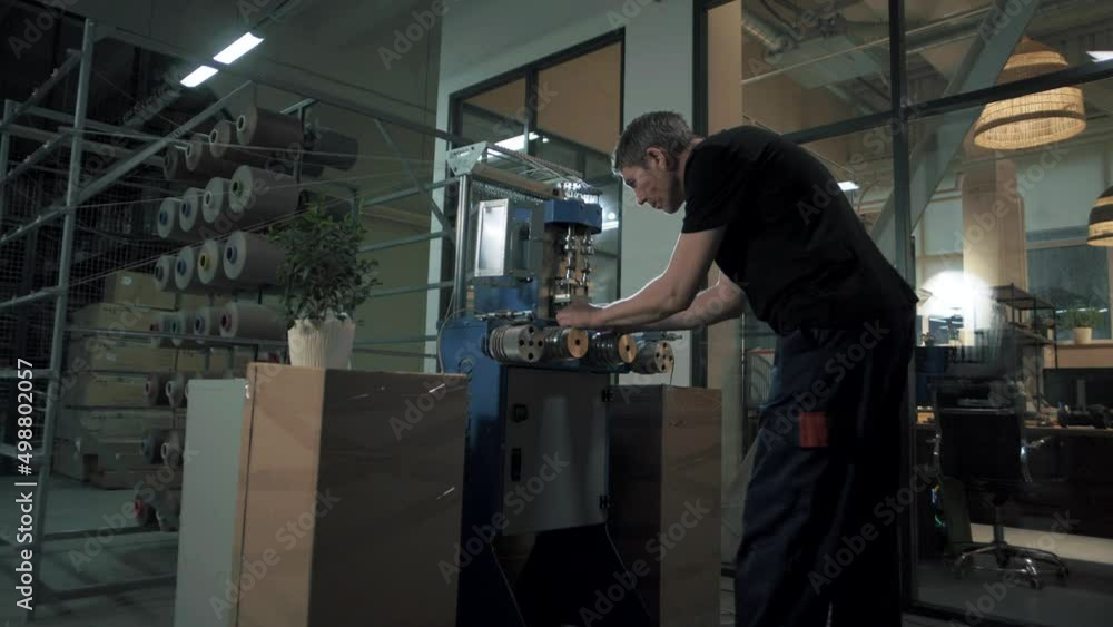 Sewing workshop worker sets up an automated machine for the production of high-quality rope from special threads. Sewing workshop worker sets up an automated machine for the production of high-quality rope from special threads.
