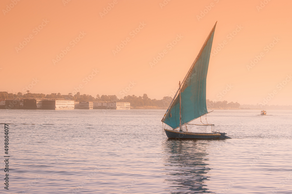 felucca is a traditional sailing boat used for tourist transport and cruise down the Nile in Luxor city in Egypt at romantic sunset time