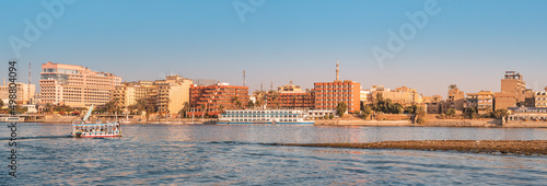 Panoramic view of traditional Egyptian ferry boats and cruise ships down the Nile with hotels of Luxor in the background