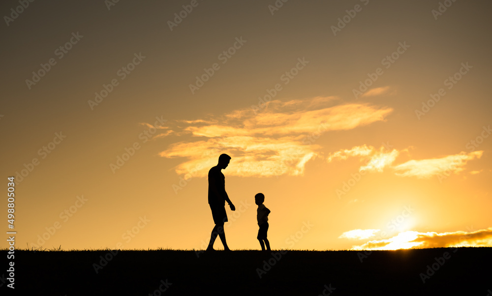 Happy father son moment. Silhouette of dad and child standing in an open field. Parenting concept. 