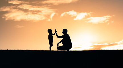 Father encouraging in child giving him a high five. Happy father son moment outdoors. Parenting and raising children concept. 