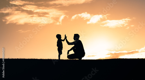 Father encouraging in child giving him a high five. Happy father son moment outdoors. Parenting and raising children concept. 
