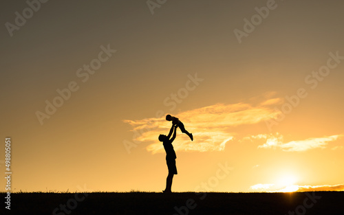 Father holding up child to the sunset sky. Happy parenting and raising children concept. 