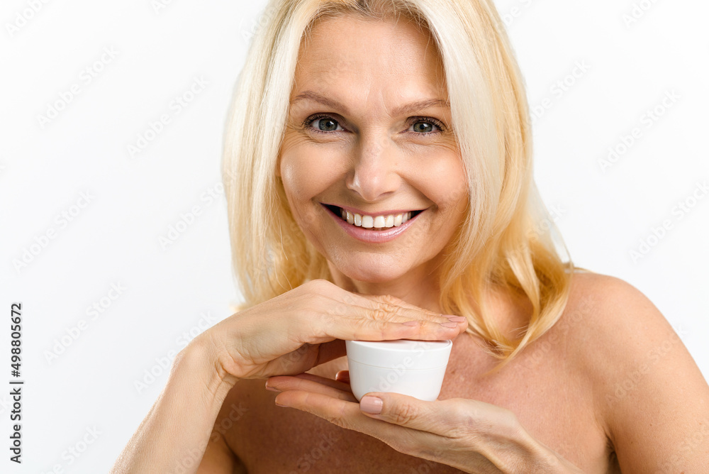 Skincare routine. Charming middle aged blonde 40s woman holding jar with anti-aging moisturizer cream, looking at the camera isolated on white background, copy space. Advertising concept Skincare routine. Charming middle aged blonde 40s woman holding jar with anti-aging moisturizer cream, looking at the camera isolated on white background, copy space. Advertising concept