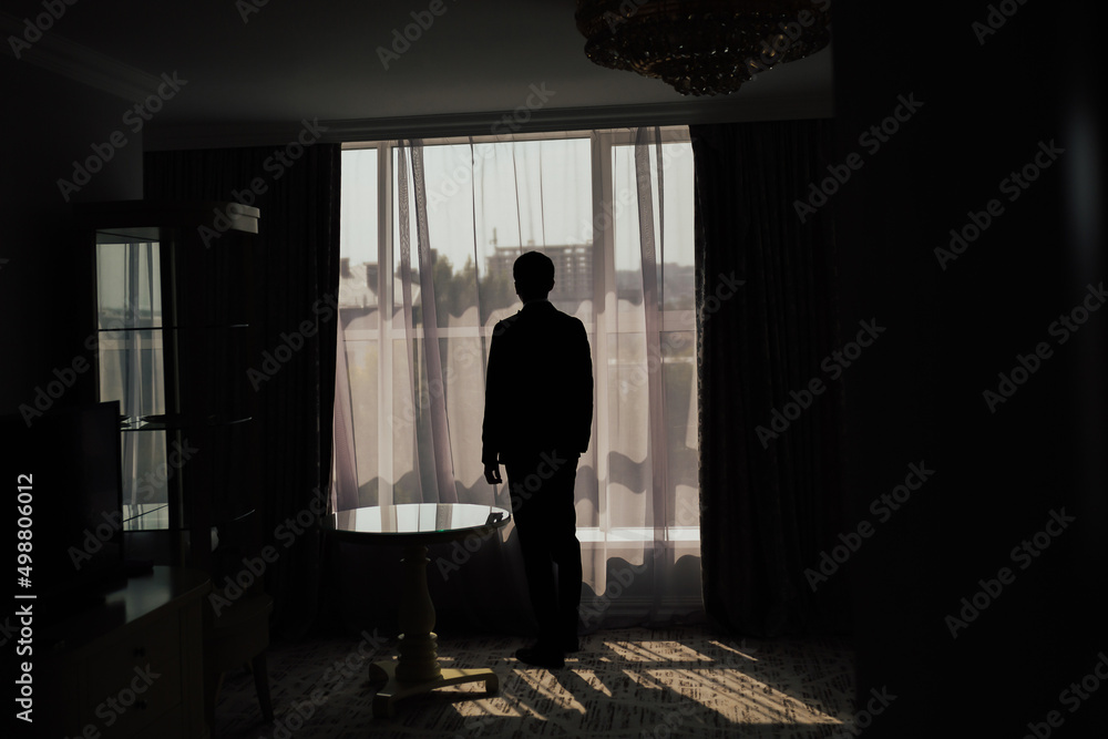 Dark silhouette of man looking through a window at a big city.