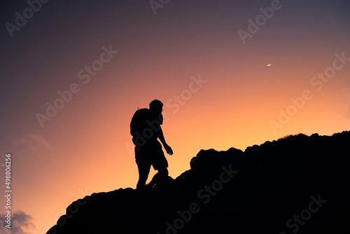 Silhouette of man hiking up mountain at dawn 