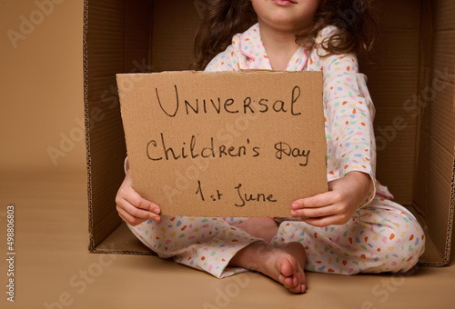 Closeup cardboard banner with social message - World Children's Day on July 1st. Little girl holding a poster calling for respect for children's rights