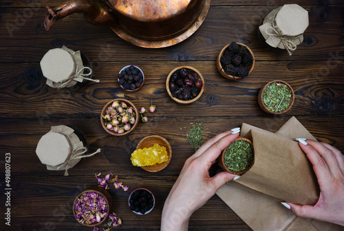 Women's hands pour a mixture of herbal tea into a bag