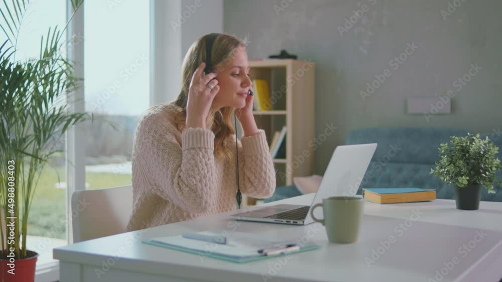 Young lady wear wireless headset making conference video call on laptop at home Young lady wear wireless headset making conference video call on laptop at home