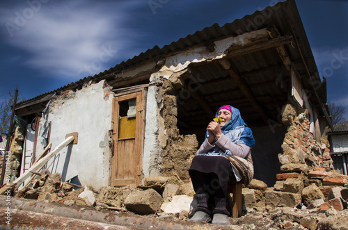 War in Ukraine. Grandmother prays for an end to the war. Ukrainian refugees. A woman in front of a house destroyed by a rocket. Consequences of the war in Ukraine. Ukrainian woman prays for peace. photo