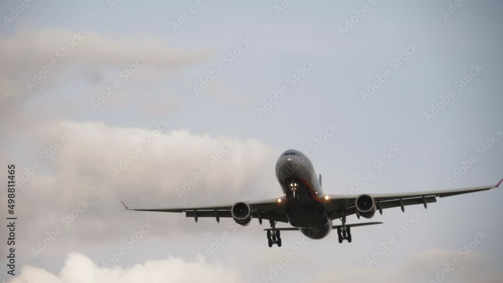 Civil aircraft flies for landing, bottom view. Jet airliner released the landing gear and is ready to land, slow motion footage of the flight. Air industry, travel and tourism concept Civil aircraft flies for landing, bottom view. Jet airliner released the landing gear and is ready to land, slow motion footage of the flight. Air industry, travel and tourism concept