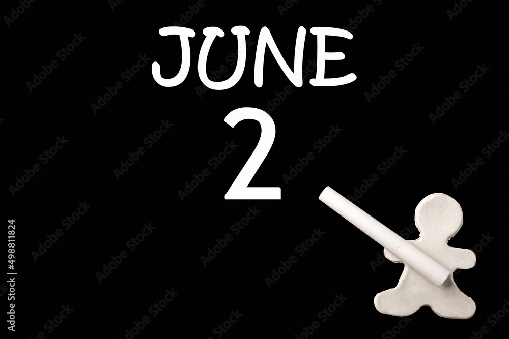 2nd day of June. A small white plasticine man writing the date 2 June on a black board. Business concept. Education concept. Summer month, day of the year concept. 2nd day of June. A small white plasticine man writing the date 2 June on a black board. Business concept. Education concept. Summer month, day of the year concept.