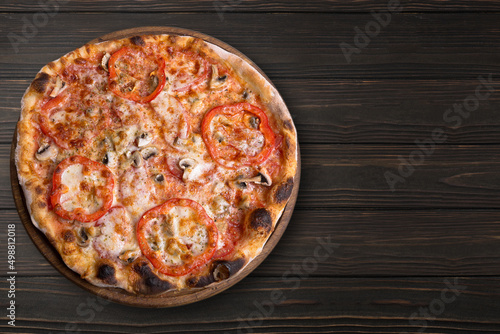 Pizza with mushrooms and tomatoes, on a round wooden board