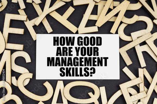 On a black surface are wooden letters and a business card with the inscription - HOW GOOD ARE YOUR MANAGEMENT SKILLS photo