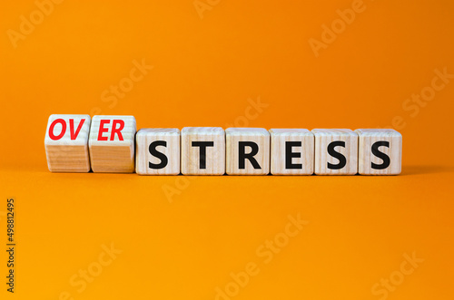 Over stress symbol. Turned wooden cubes and changed concept words Stress to Over stress. Beautiful orange table orange background, copy space. Psychlogical over stress concept.