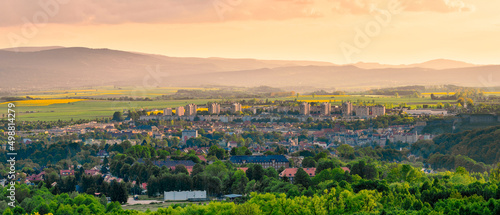 Kłodzko, panorama of the city in the valley against the background of the mountains lit by bright sun at sunset.