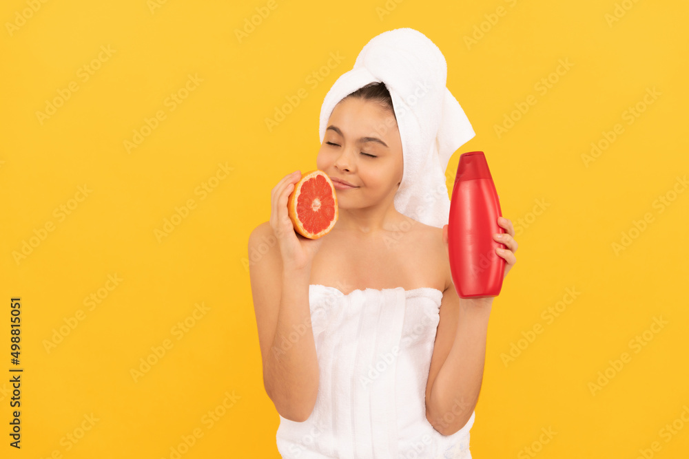smiling teen girl in towel with grapefruit shampoo bottle on yellow background smiling teen girl in towel with grapefruit shampoo bottle on yellow background
