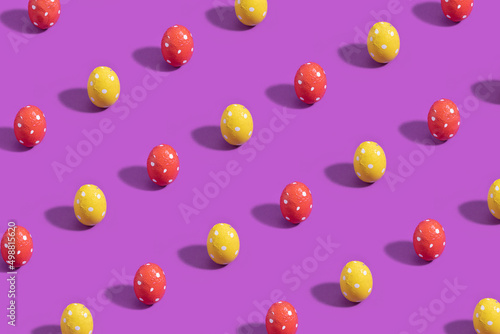 Chocolate Easter eggs wrapped in dotted red and yellow foils on a purple background.
