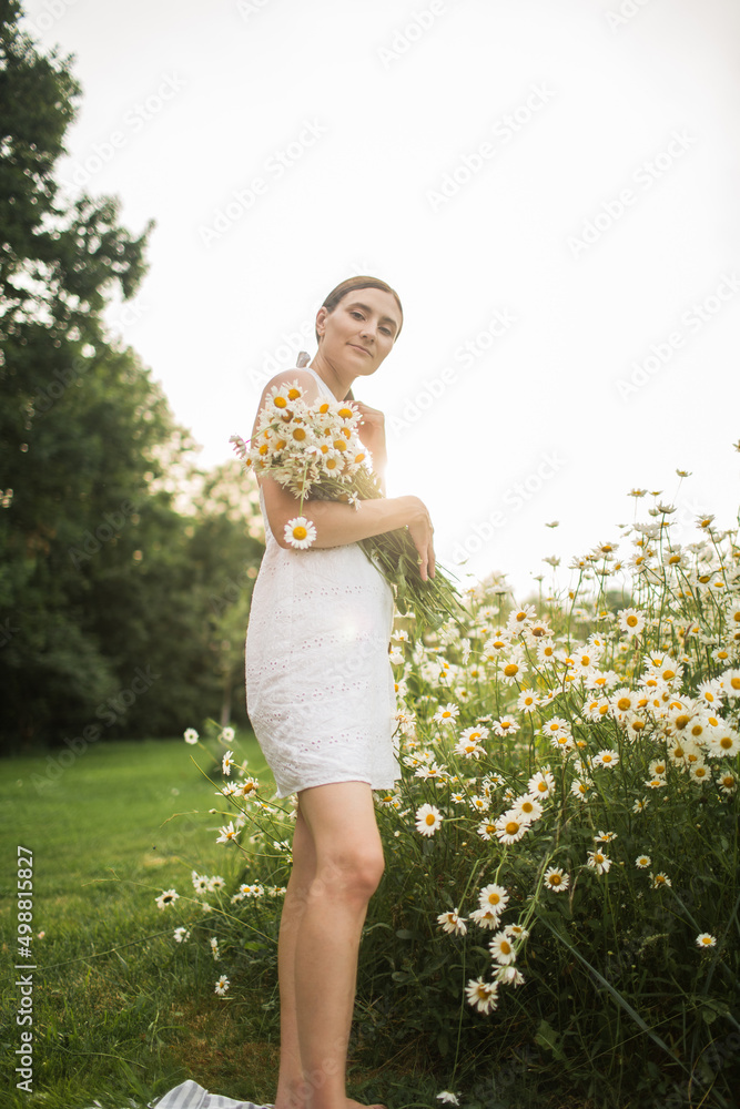 a girl with a large bouquet of daisies sits in nature