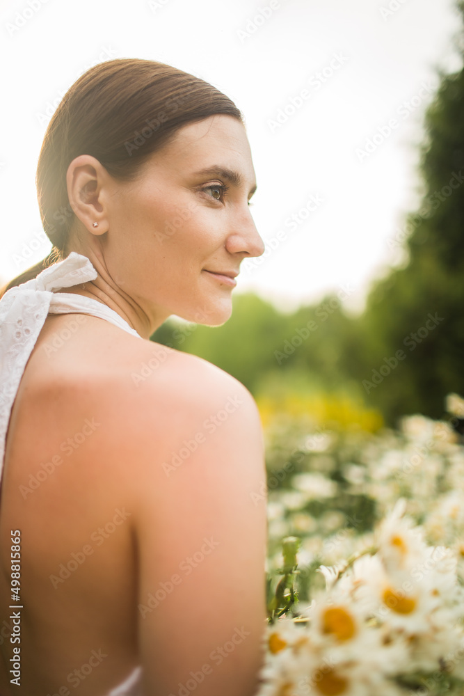a girl with a large bouquet of daisies sits in nature