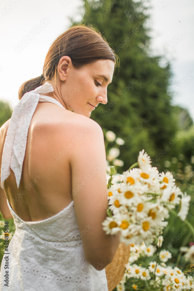 a girl with a large bouquet of daisies sits in nature