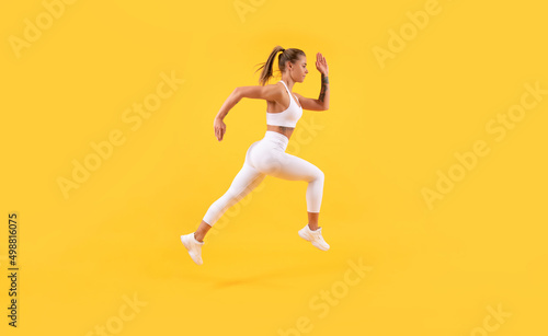 energetic fitness woman runner running on yellow background