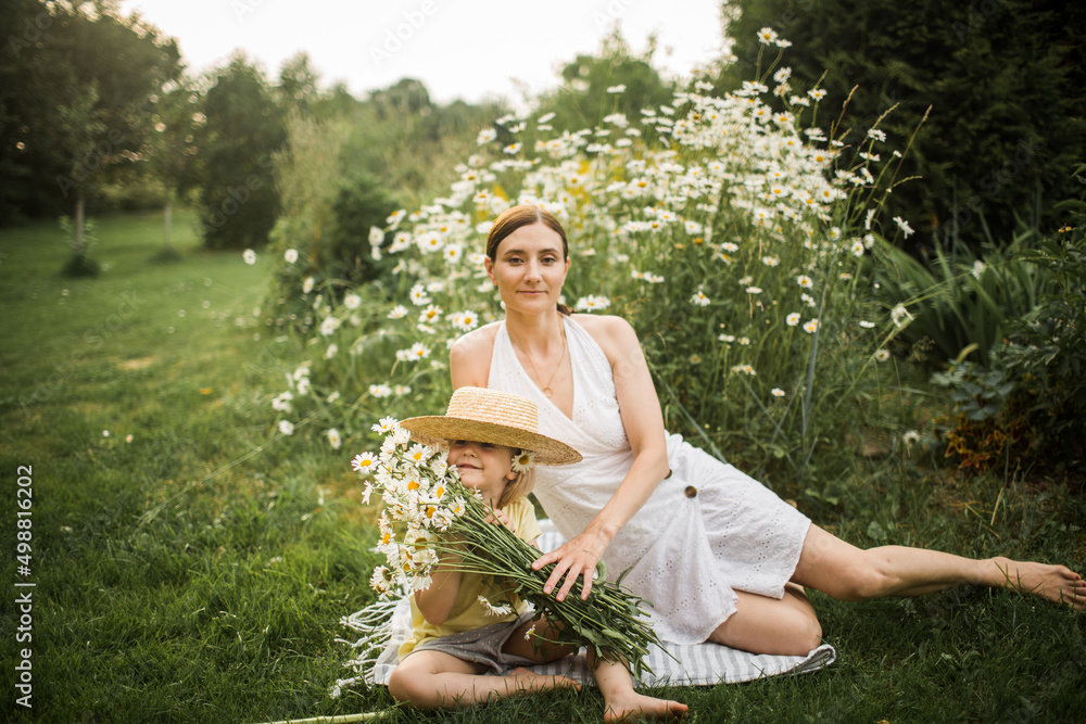 mother plays with her daughter, relax, collect daisies