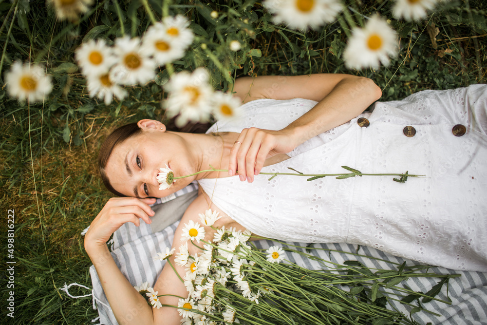 young woman lies in daisies